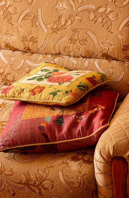 A white upholstered sofa with deep button tufting on the backrest and rolled arms, positioned against a white paneled wall with decorative molding. The sofa sits on dark wooden legs on a light wooden